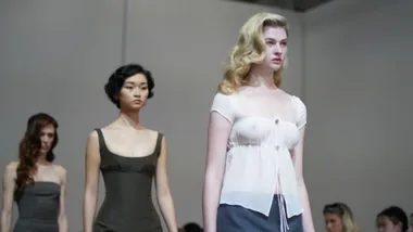 Models walking down the runway in elegant dresses at a fashion show.