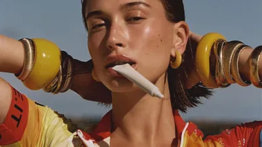 A woman holding a white tube between her teeth wearing bright coloured bangles.