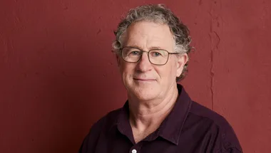Dr Vincent Hurley wearing a burgundy shirt pictured in front of a dark red wall